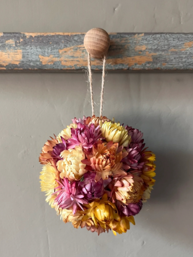 Dawn Dried Flower Bauble. A bauble made of yellow, orange and pink dried flowers.