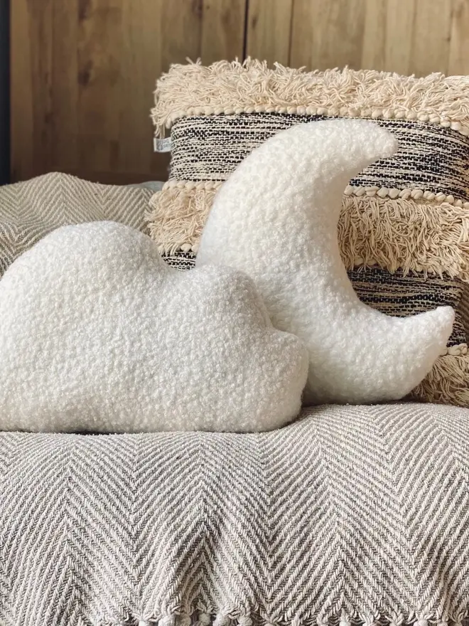 boucle moon and cloud pillow set. a white moon and white cloud cushion on a sofa.