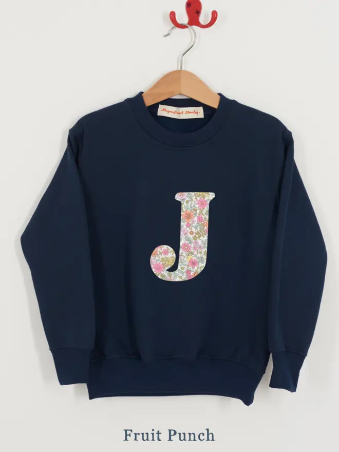 a kids navy sweatshirt with the initial J personalised in floral liberty print on the front