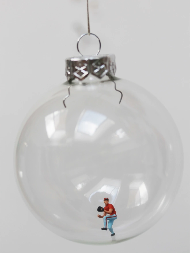 Miniature figure of a baseball pitcher in a glass Christmas bauble