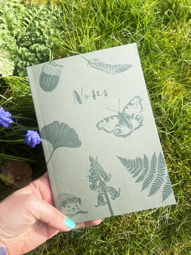 Front of the notebook in front of a green bush.