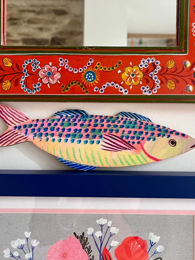 wooden mackerel wall decoration. mackerel decoration propped up on mantelpiece.