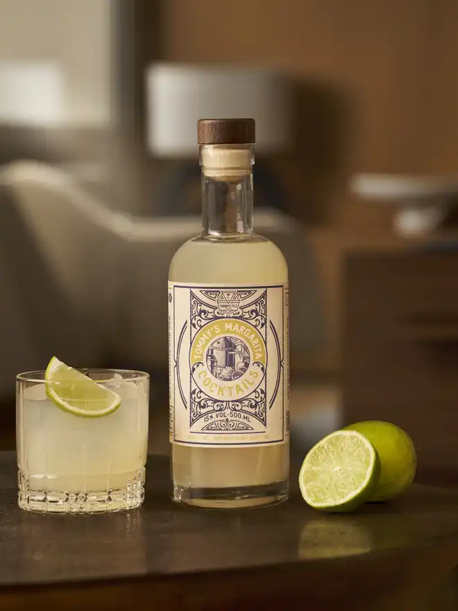 Tommy's Fizz Margarita Cocktail, a bottle of Tommy's Margarita cocktail next to an empty glass being filled from another bottle.