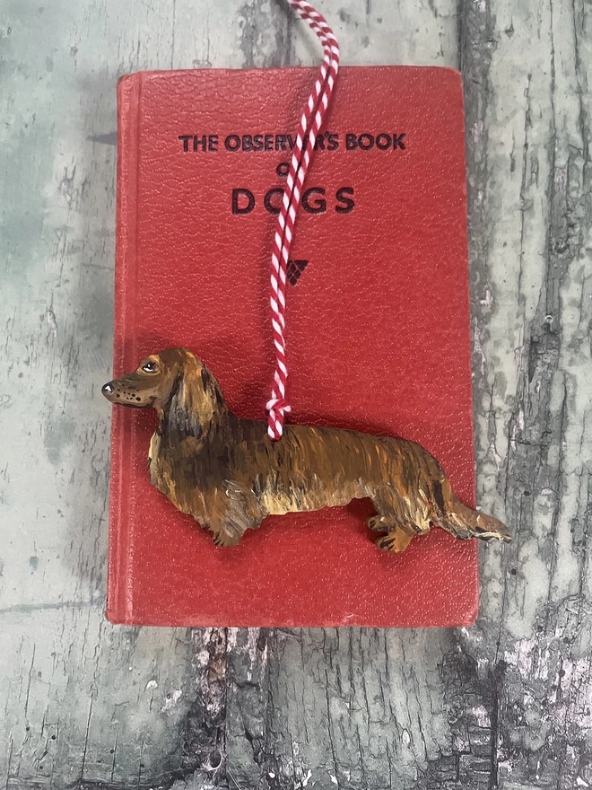 Long - Haired Dachshund Christmas Tree Decoration placed on a book about dogs