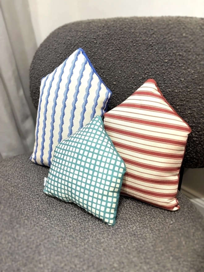 Back of Set of 3 house cushions lying on a brown chair