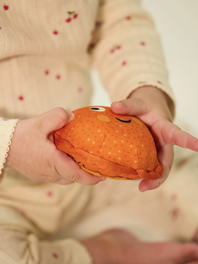 baby holding squishy orange toy