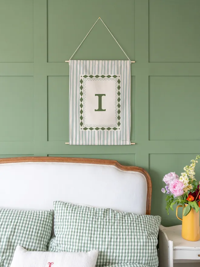 Stripe Initial Fabric Banner, hanging on a green wall. 
