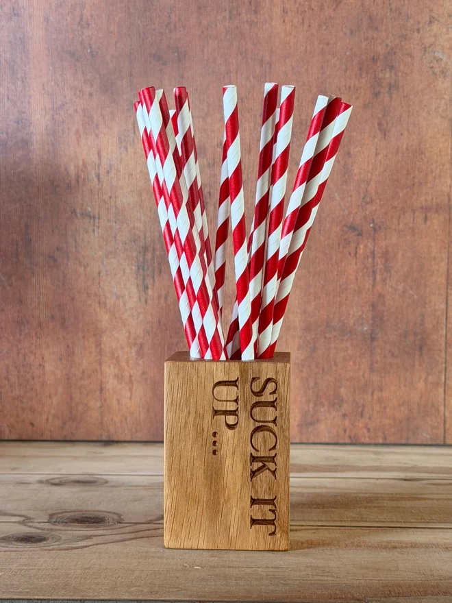 Stripy straws in a straw cup with engraving that says Suck it up...