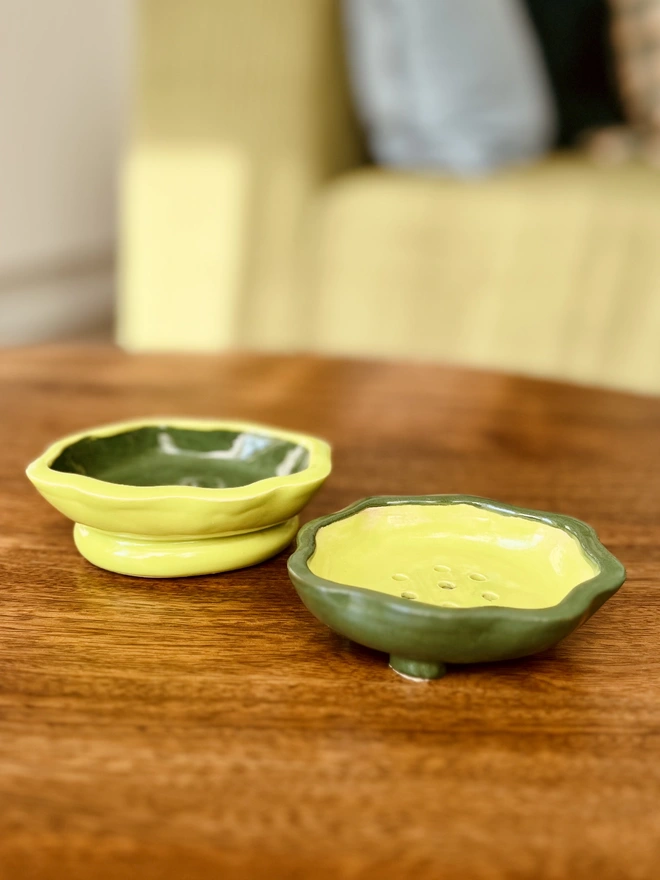 wavy rimmed soap dish held in the palm of a hand against a fabric background. the soap dish is lime green on the outside with a dark green inside