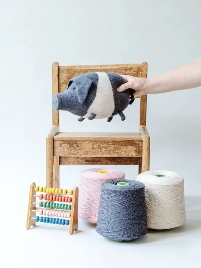 sadddleback pig plush being held over chair