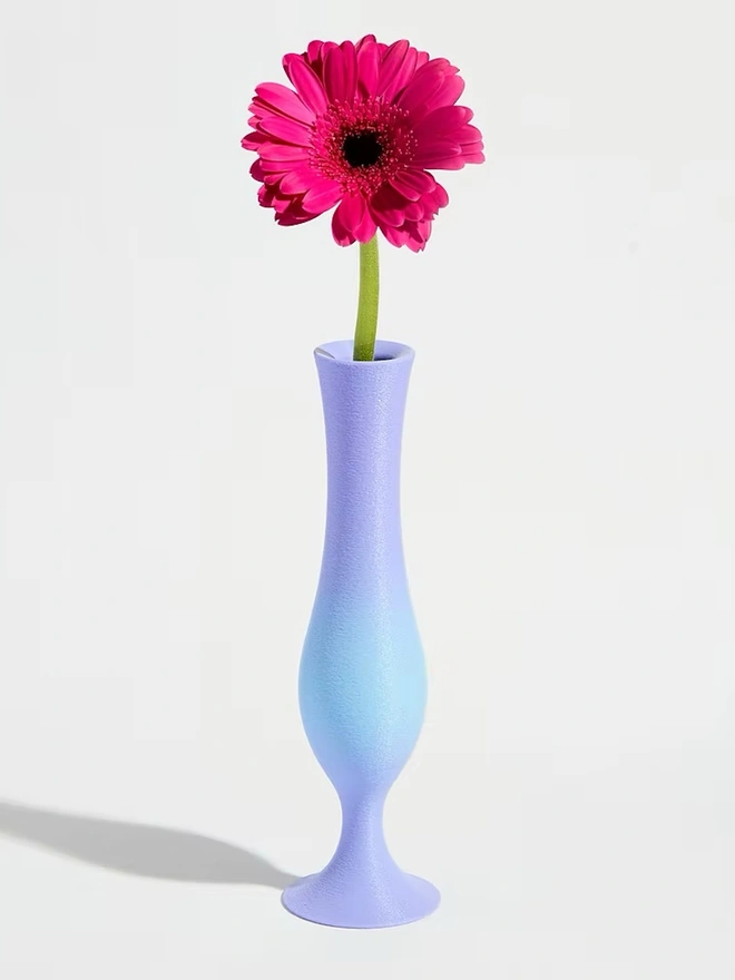 3d printed vase in blue and purple stripes with bright pink flower