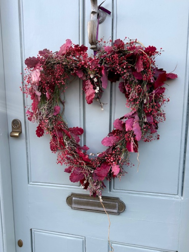 Dried Woodland Pink Heart Wreath hanging on a grey door