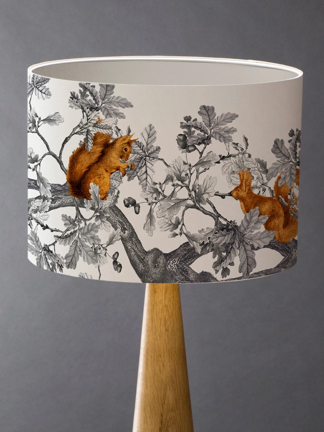 A decorative lampshade featuring red squirrels among oak leaves and acorns, inspired by the British countryside and woodland wildlife.