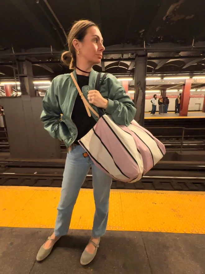 woman holding mauve striped bag on NY subway