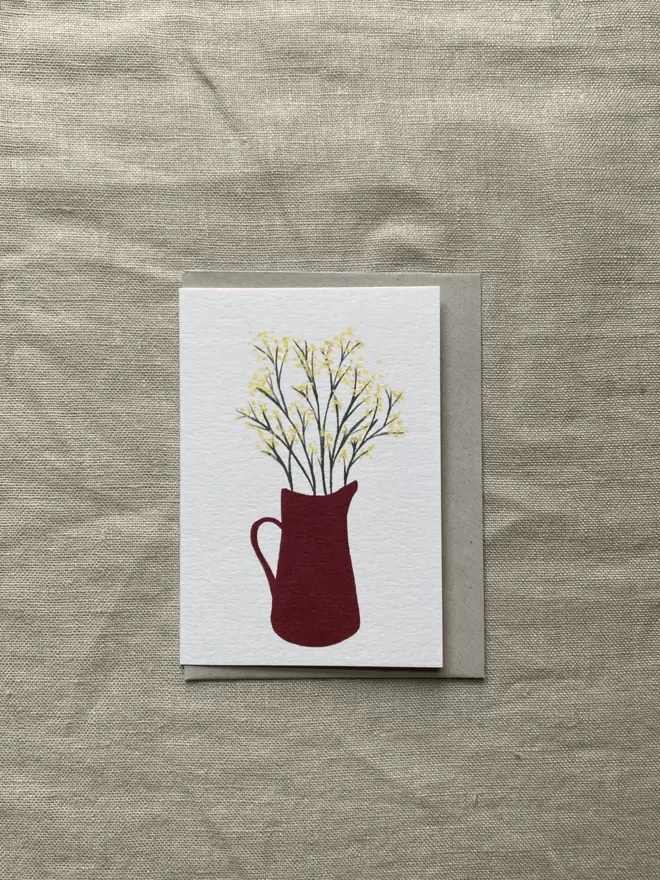 greetings card with bright yellow cut mimosas flowering in brown jug.