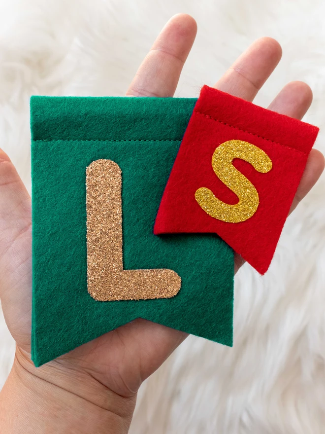 A hand holding 2 example felt flags, one large, one small.