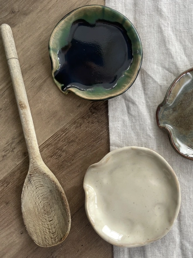 A green and birch Ceramic Spoon Rest on a table with a linen tablecloth and a wooden spoon