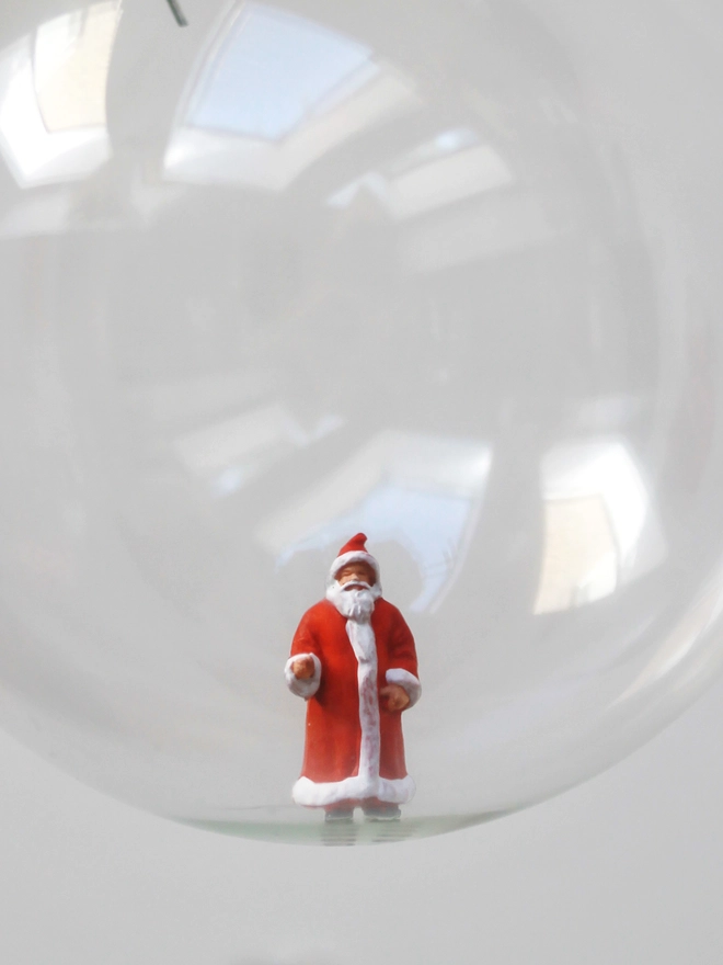 Miniature figure of Santa Claus in a glass Christmas bauble  