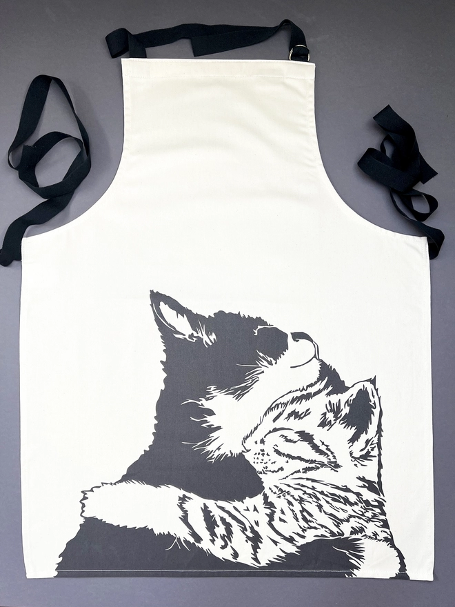 Full view of our cuddle time apron which is an design of a black and white cat cuddling a Tabby cat