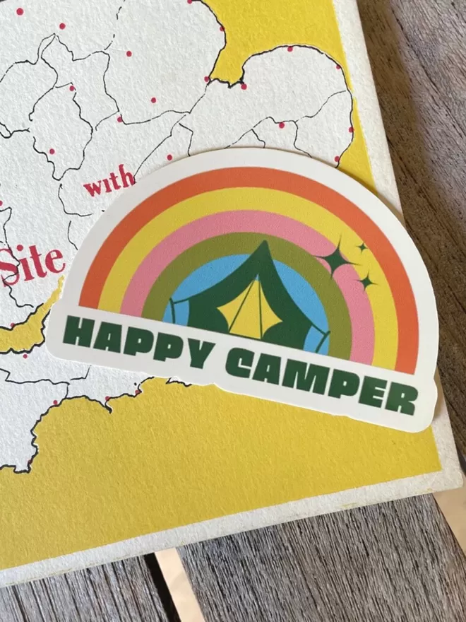 Happy Camper Vinyl Sticker laying on a yellow map