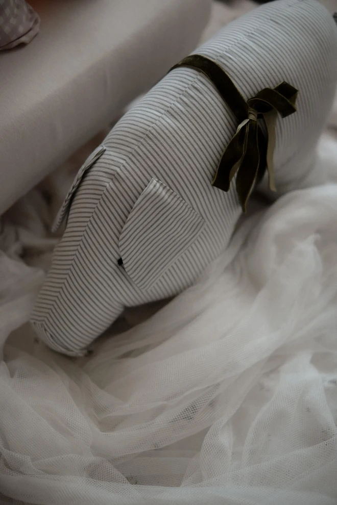 Cotton Pig Plushie, a cotton pig plushie sitting on a decorated bed. 