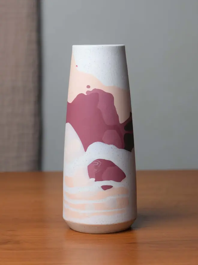 vase on wooden table, vase has streaky pattern in shades of purple, brown, and pale pink