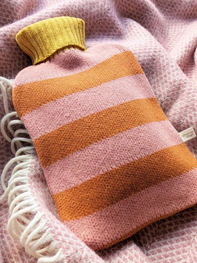 COLOURFUL HOT WATER BOTTLE COVER DISPLAYED ON A ON A BLANKET