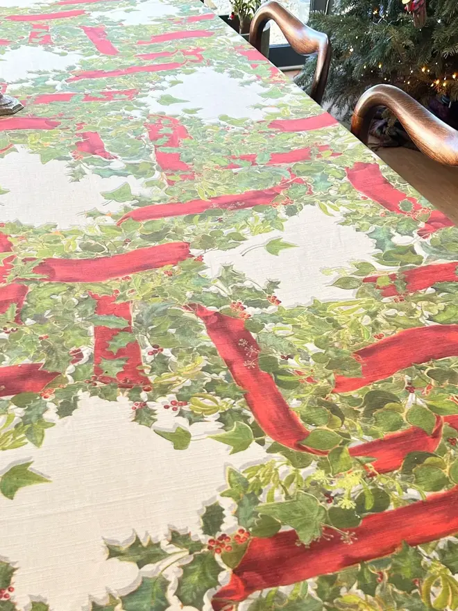 christmas garland lattice tablecloth. a tablecloth printed with holly, ivy and mistletoe on a table.