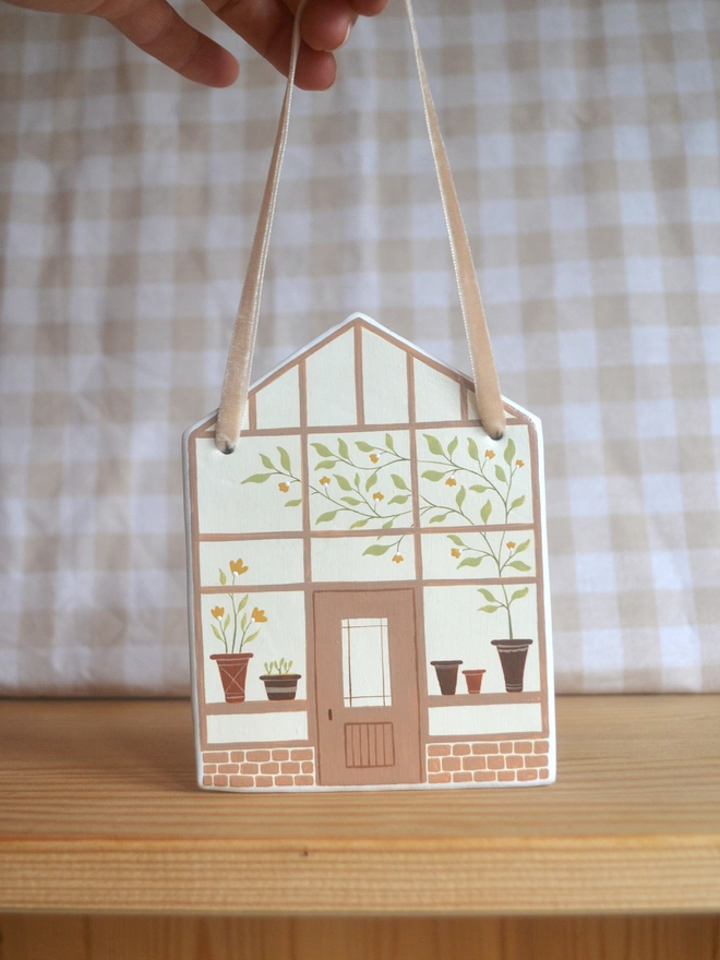 white ceramic hanging decoration with brown greenhouse illustration design