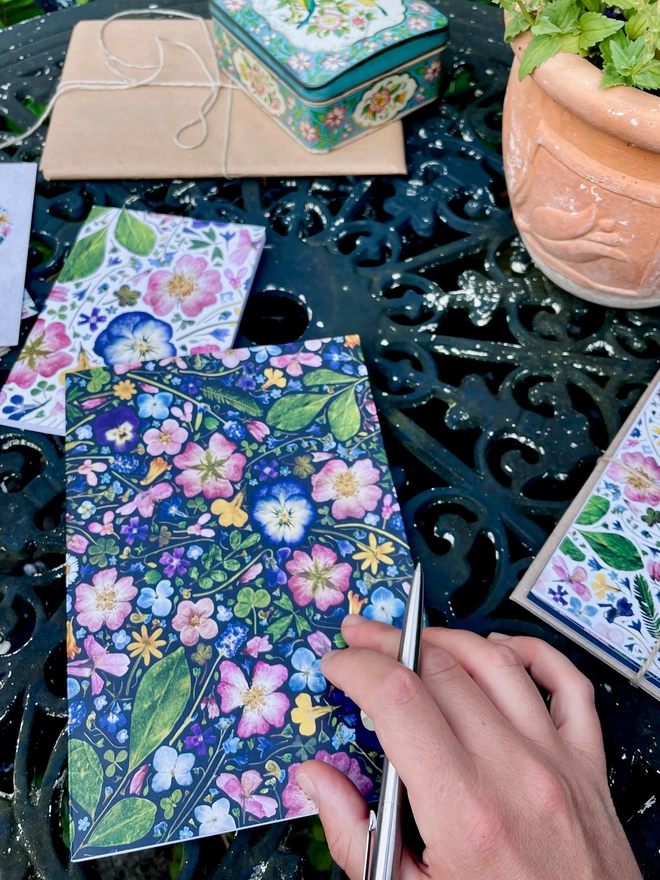 Botanical Notebook with Flower Cover with Pressed Hydrangea, Viola, Cornflower, Lavender, Dog-Rose, Daisy, Verbena, Buttercup, and Forget-Me-Not. On Garden Table