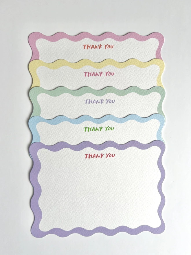 A selection of five wavy edged notecards with different coloured borders and the words thank you written in capital letters at the top of each card