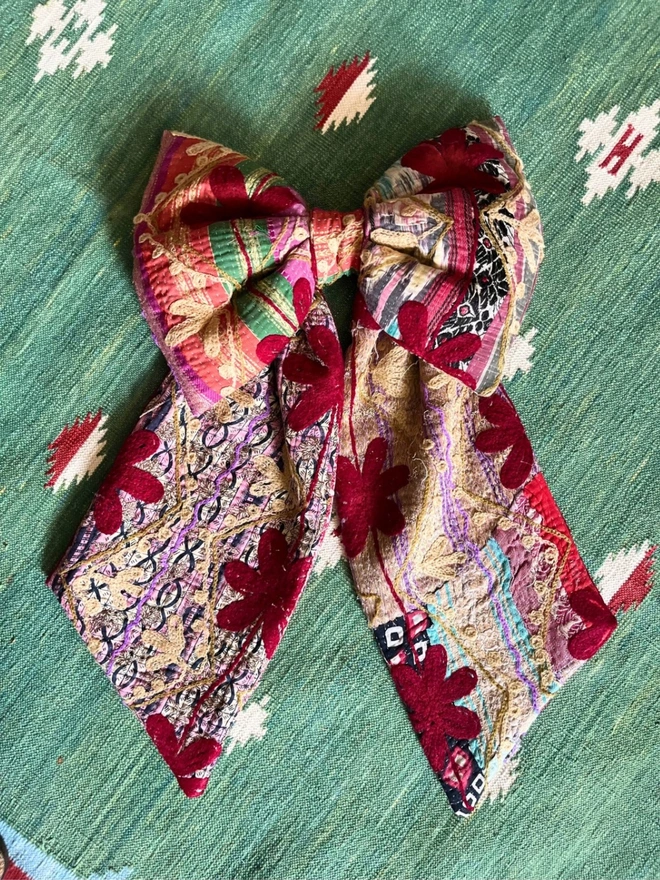 Large decorative bow, handmade from vintage kantha fabric in reds and pinks with additional embroidery flowers 