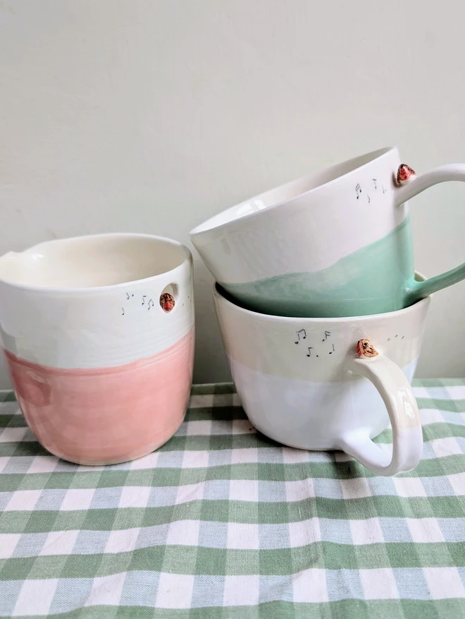 pink jug and white and green ceramic cup with a tiny robin bird on the handle with bird prints and musical notes on the mugs