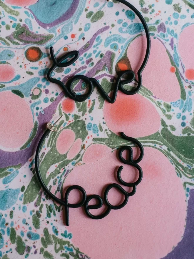 Love and Peace black earrings by Zoe Sherwood seen on marble paper.