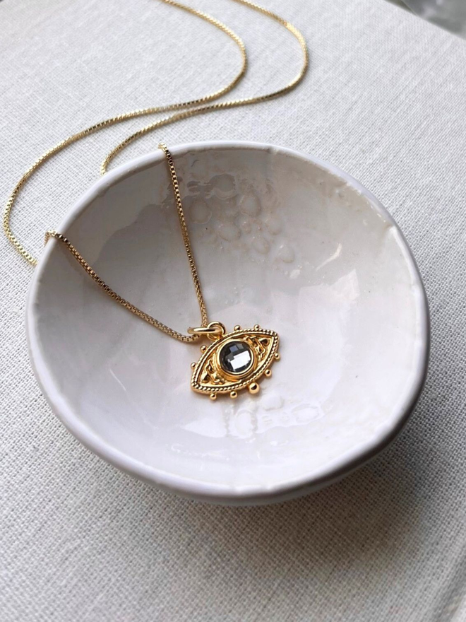 gold evil eye charm necklace with a grey quartz stone on a gold box chain necklace