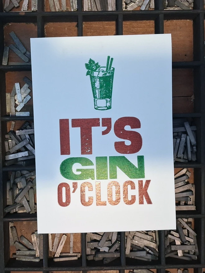 A greetings card printed in burgundy and green with the text 'It's Gin O'Clock'