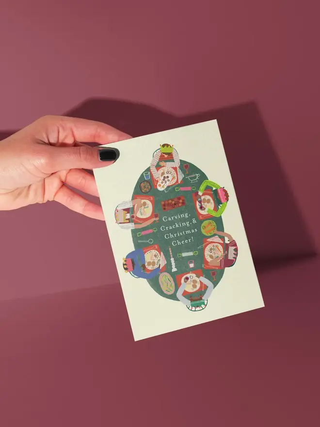 funky festive feast illustrated christmas card. illustration of a festive christmas dinner on a white card, photographed against a red background.