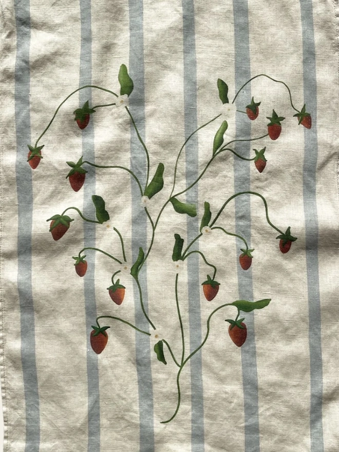'Strawberry Vines' Linen Tea Towel, a person holding a tea towel with a strawberry motif on it. 