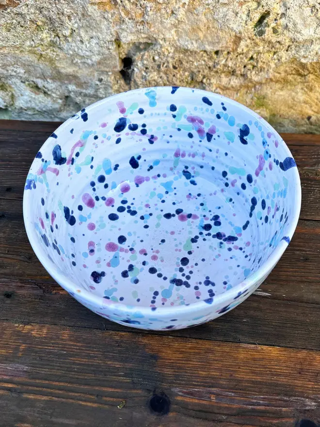 Sweetpea Ramen Bowl, a colourful ramen bowl sat on a wooden surface in front of a brick backdrop. 