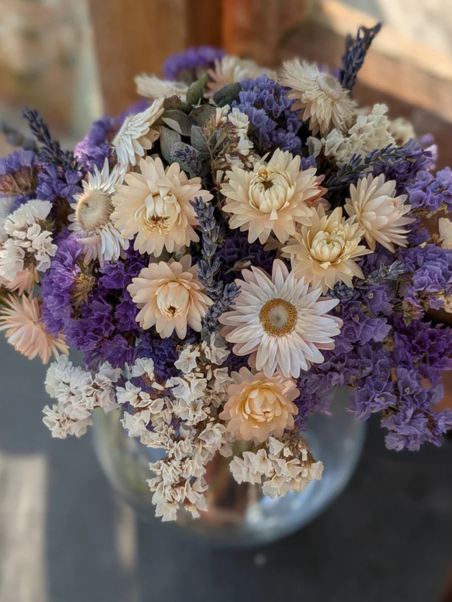 lavender sea spray dried flower bouquet. bouquet of purple dried flowers in a round glass vase.