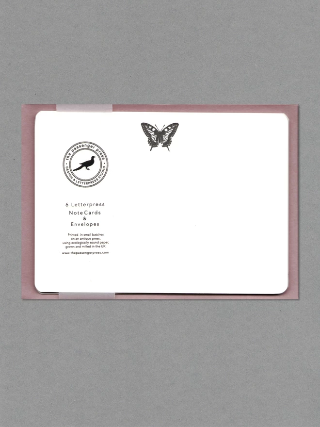 Pack of white notecards with a black butterfly at top and a see-through belly band at top with on top of mulberry envelopes