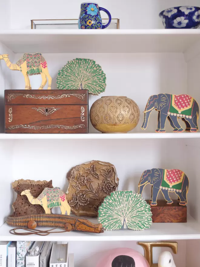 2 elephant, 2 camel and 2 peacock being displayed on a shelf 