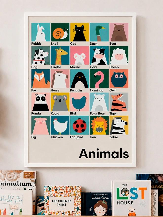 Bright animal poster featuring lots of different animals. Hanging on a wall above a bookshelf with childrens books and soft rabbit toy