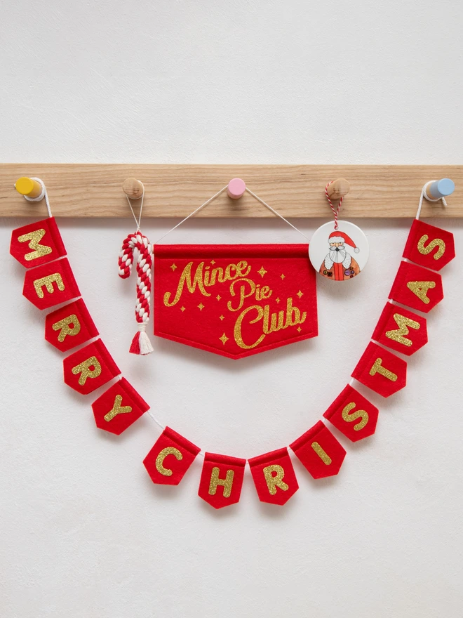 Red and gold MERRY CHRISTMAS bunting hanging underneath a MINCE PIE CLUB banner in matching colours