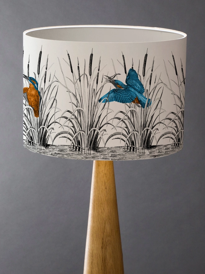 Handmade lampshade featuring vibrant kingfishers among bulrushes in a whimsical countryside-inspired design, combining nature, colour, and artisan style.