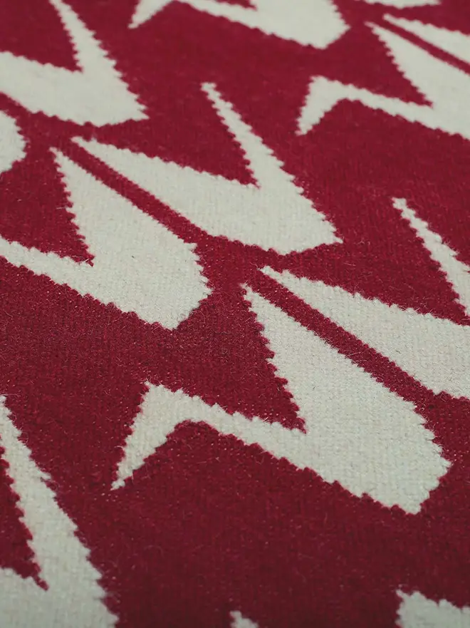 Crane Flatweave Rug, a colourful rug sitting on a plain surface. 