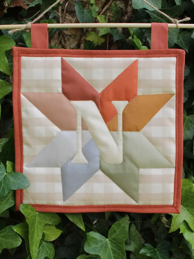 personalised initial quilt hanging. a hand-sewn hanging quilt with a star design in the centre, alongside the initial 'N'.