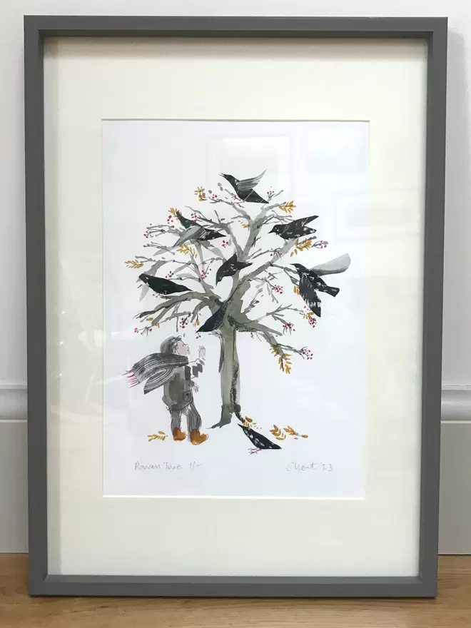 Illustrated framed print of Esther Kent illustration, showing girl standing by a bare rown tree covered in black birds and red berries, in a grey frame